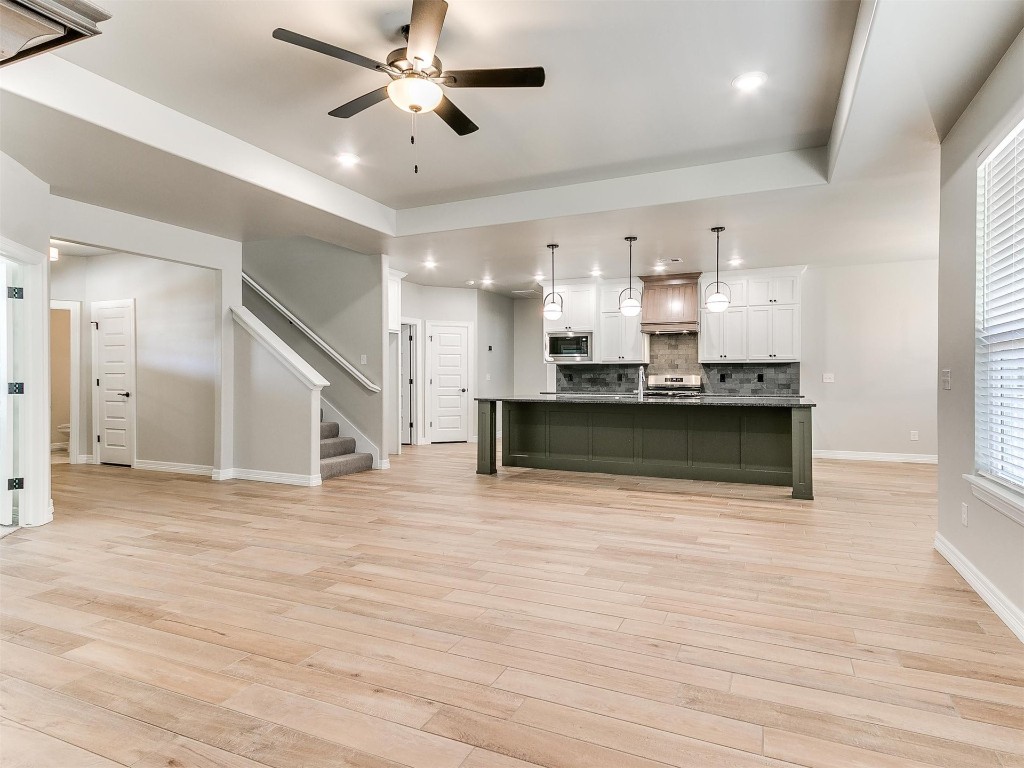 11000 Treemont Lane, Oklahoma City, OK 73162 kitchen with ceiling fan, white cabinets, light hardwood / wood-style floors, backsplash, and stainless steel microwave