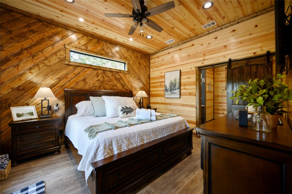 41 Oak Creek Trail, Broken Bow, OK 74728 bedroom with wooden walls, a barn door, dark hardwood / wood-style floors, and wooden ceiling