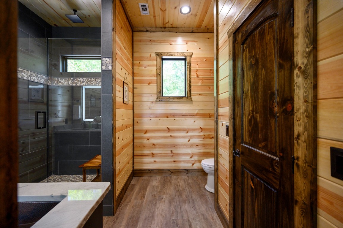 41 Oak Creek Trail, Broken Bow, OK 74728 bathroom featuring walk in shower, toilet, wood-type flooring, wooden walls, and wood ceiling
