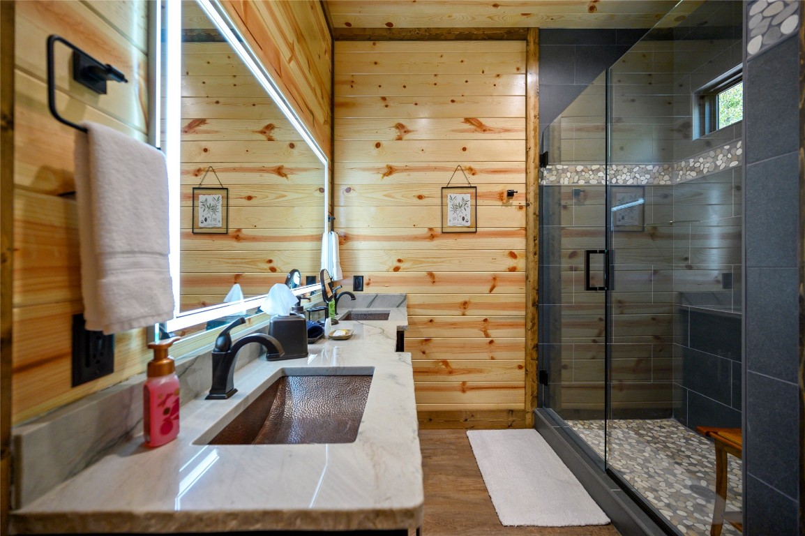 41 Oak Creek Trail, Broken Bow, OK 74728 bathroom featuring walk in shower, vanity, wooden walls, and hardwood / wood-style flooring