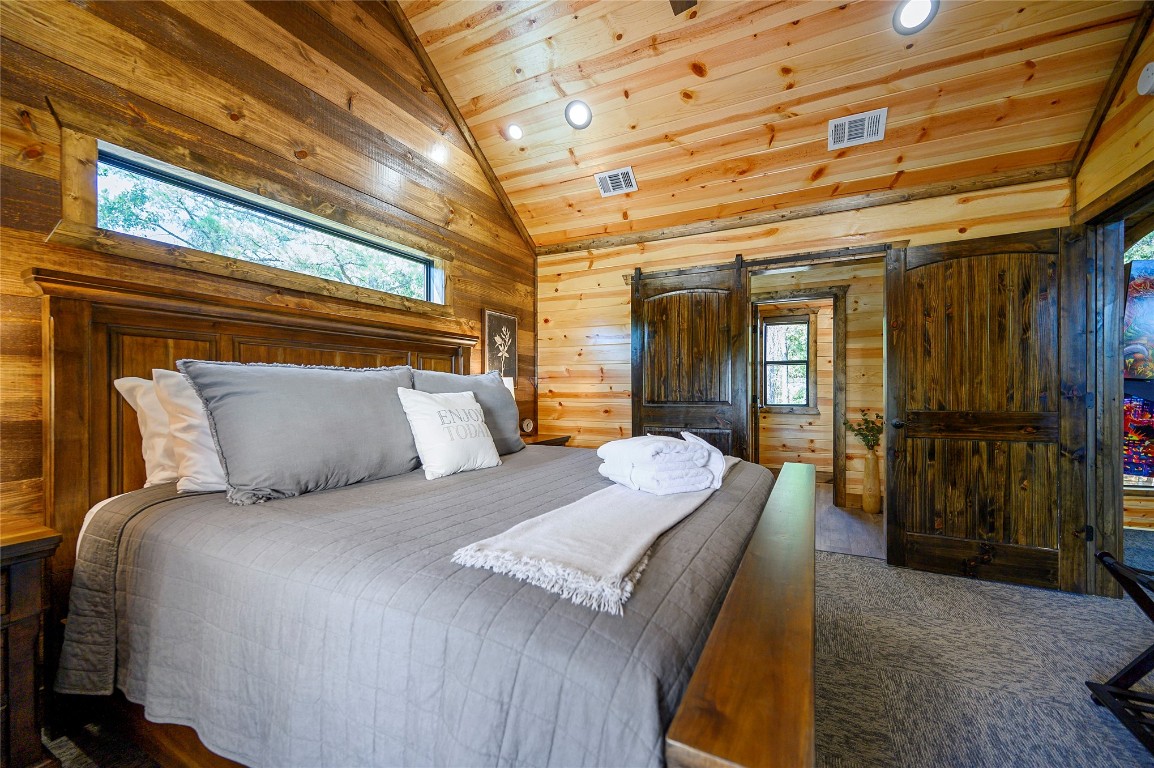 41 Oak Creek Trail, Broken Bow, OK 74728 bedroom with high vaulted ceiling, a barn door, and wood ceiling