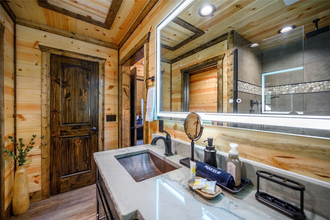 41 Oak Creek Trail, Broken Bow, OK 74728 bathroom with wood ceiling, wooden walls, sink, and hardwood / wood-style flooring