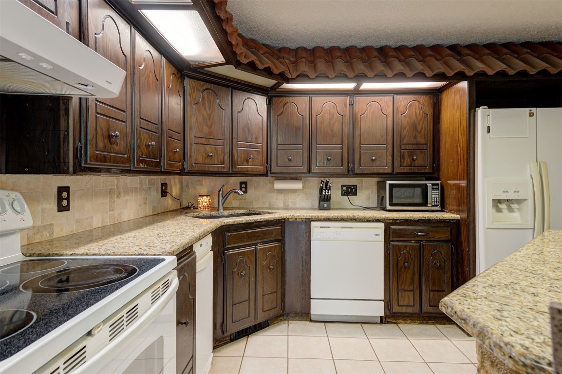 1517 S Spring Creek Drive, Mustang, OK 73064 kitchen with sink, white appliances, light tile flooring, tasteful backsplash, and dark brown cabinets