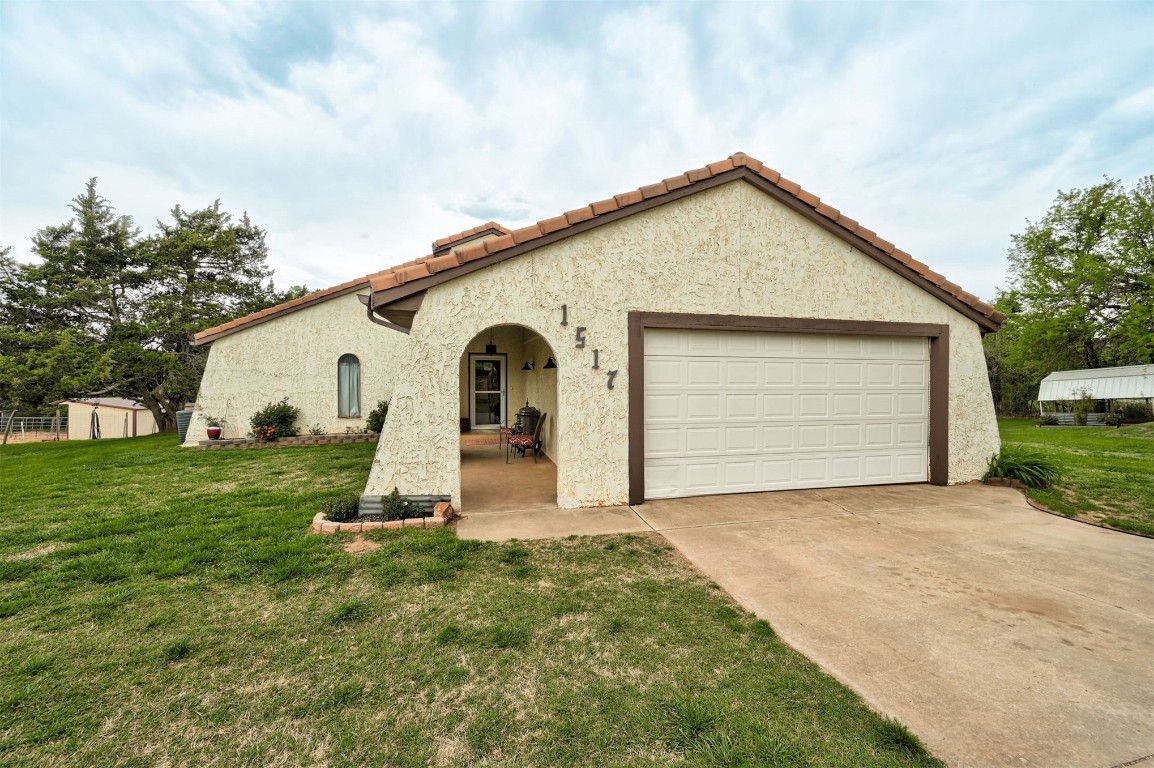 1517 S Spring Creek Drive, Mustang, OK 73064 mediterranean / spanish-style house featuring a garage and a front yard
