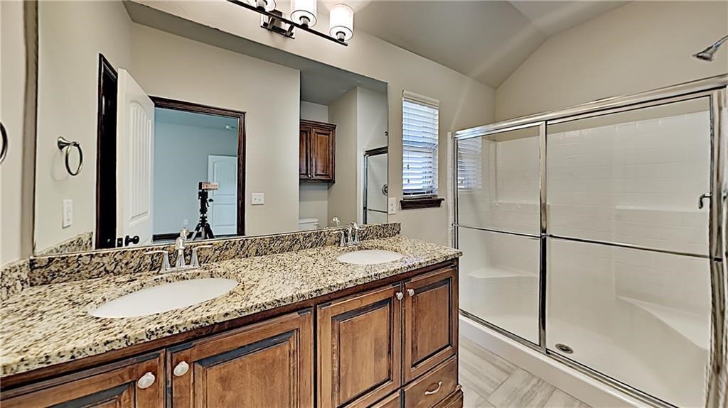 12728 NW 137th Street, Piedmont, OK 73078 bathroom featuring tile flooring, double vanity, vaulted ceiling, and walk in shower