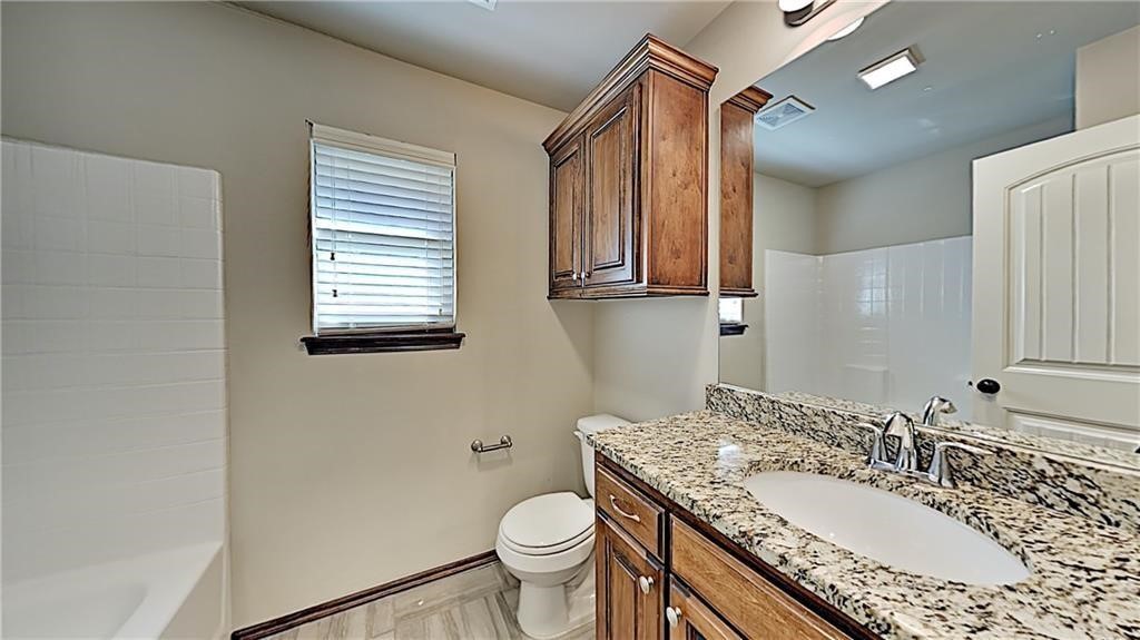 12728 NW 137th Street, Piedmont, OK 73078 full bathroom featuring shower / tub combination, vanity with extensive cabinet space, and toilet