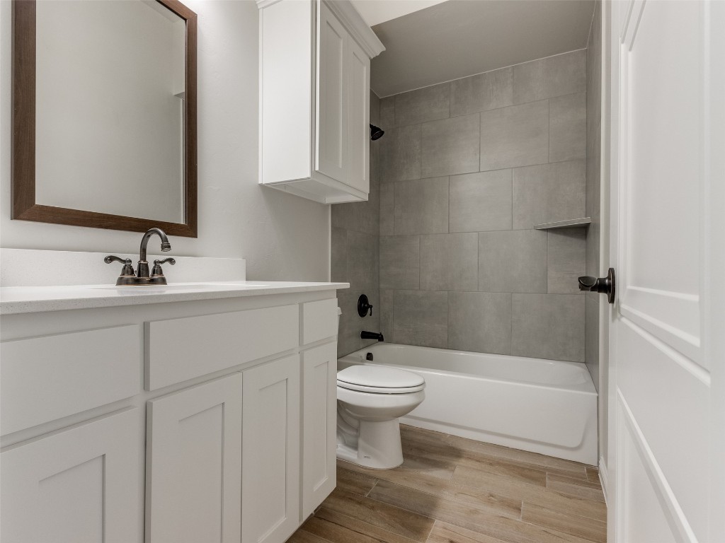 9009 NE 139th Street, Jones, OK 73049 full bathroom with hardwood / wood-style floors, tiled shower / bath, vanity, and toilet