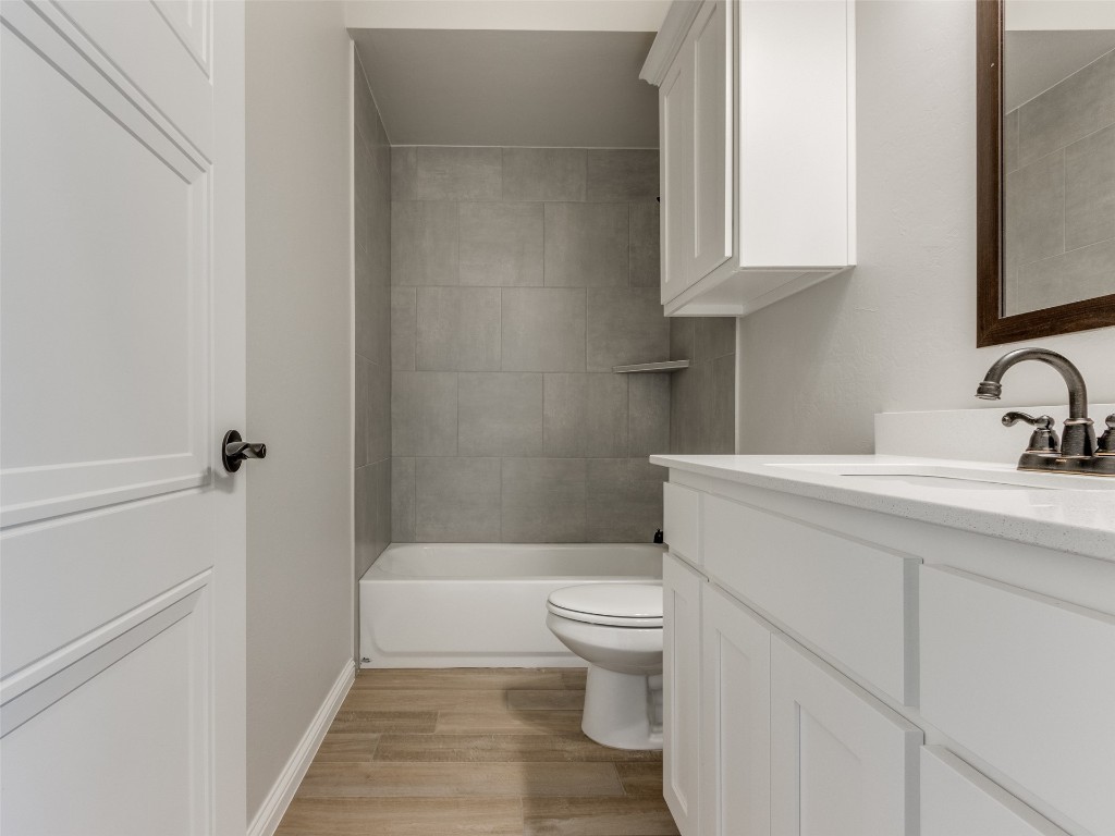 9009 NE 139th Street, Jones, OK 73049 full bathroom featuring hardwood / wood-style floors, vanity, tiled shower / bath combo, and toilet