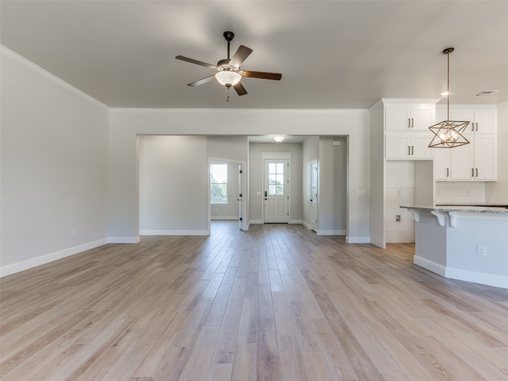9009 NE 139th Street, Jones, OK 73049 unfurnished living room with light hardwood / wood-style floors, crown molding, and ceiling fan