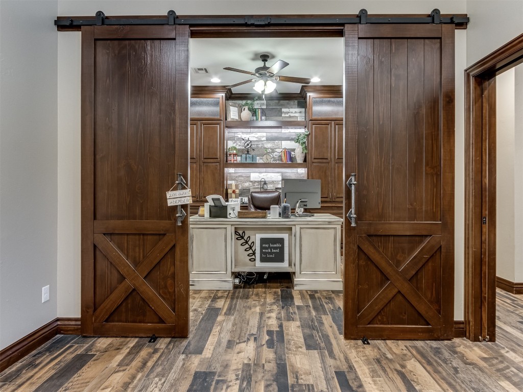9701 Nawassa Drive, Midwest City, OK 73130 bar featuring ornamental molding, ceiling fan, dark wood-type flooring, and a barn door