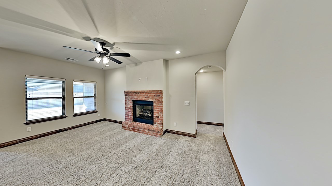 10716 NW 18th Street, Yukon, OK 73099 unfurnished living room with light carpet, ceiling fan, and a brick fireplace