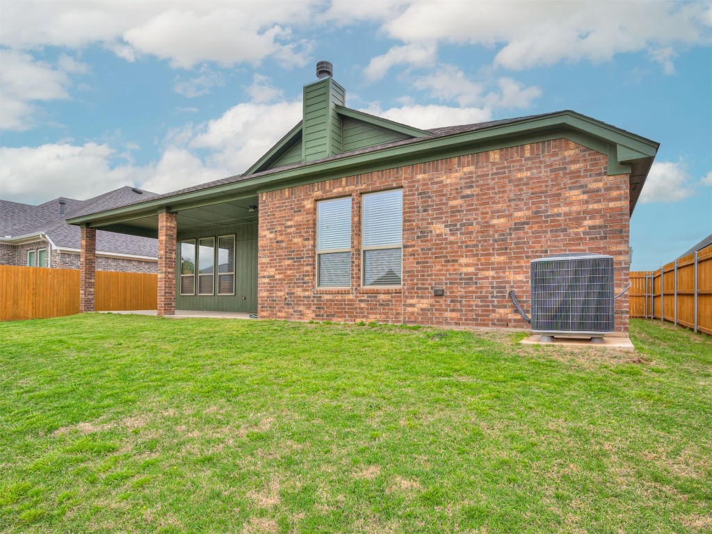 10416 NW 34th Street, Yukon, OK 73099 back of property featuring a yard and central AC unit