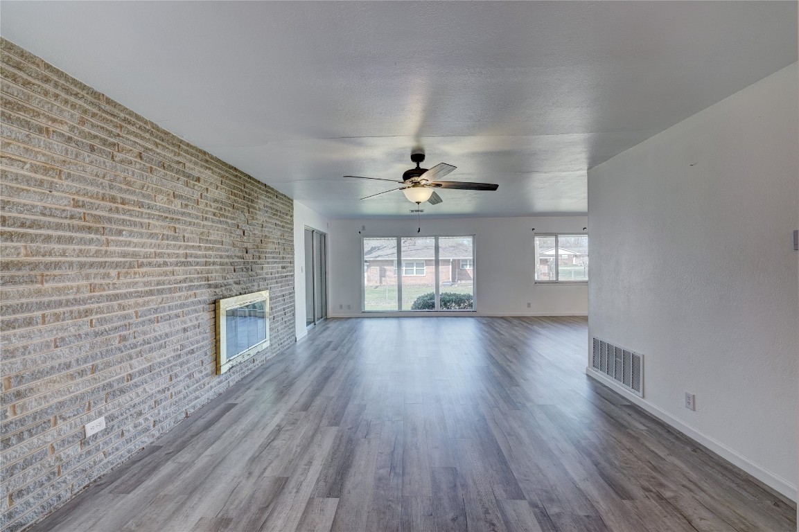 1419 Crescent, Bartlesville, OK 74006 unfurnished living room featuring a wealth of natural light, dark hardwood / wood-style flooring, and brick wall