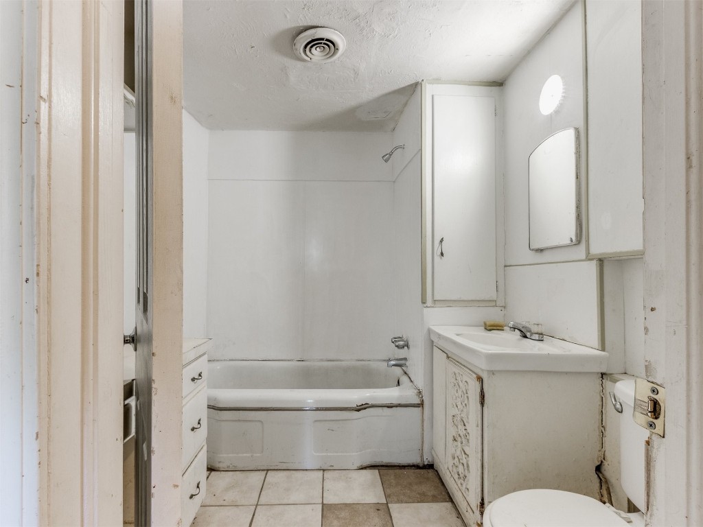 4900 S Blackwelder Avenue, Oklahoma City, OK 73119 full bathroom featuring tile floors, vanity, shower / bath combination, toilet, and a textured ceiling
