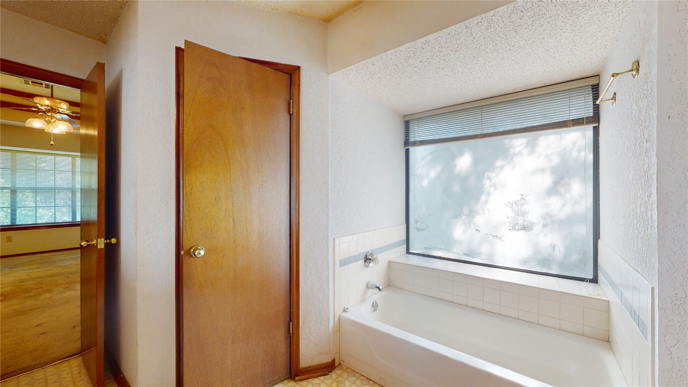 3100 SW 93rd Street, Oklahoma City, OK 73159 bathroom featuring a bathing tub, ceiling fan, tile floors, and a textured ceiling