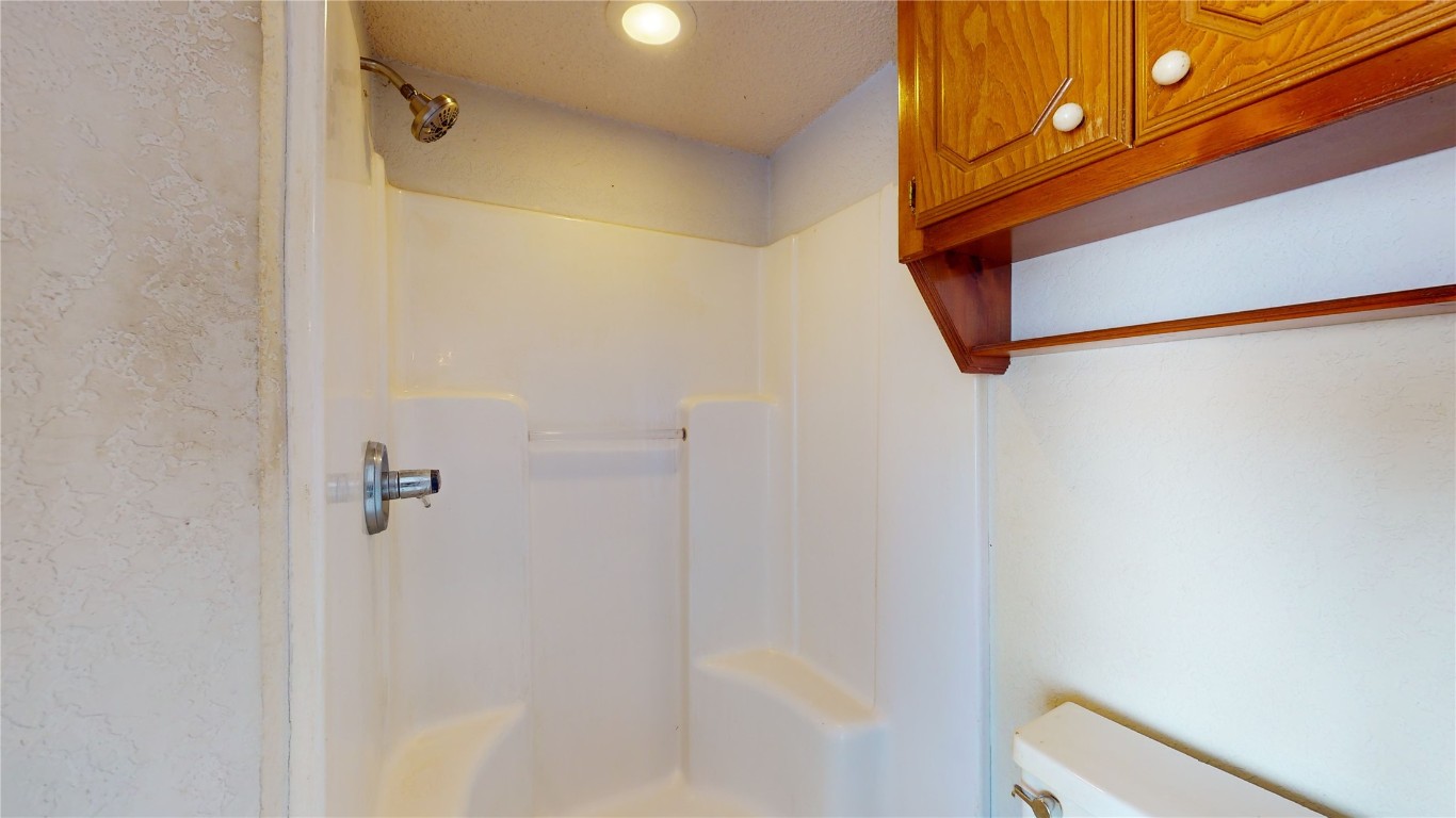 3100 SW 93rd Street, Oklahoma City, OK 73159 bathroom with walk in shower, toilet, and a textured ceiling