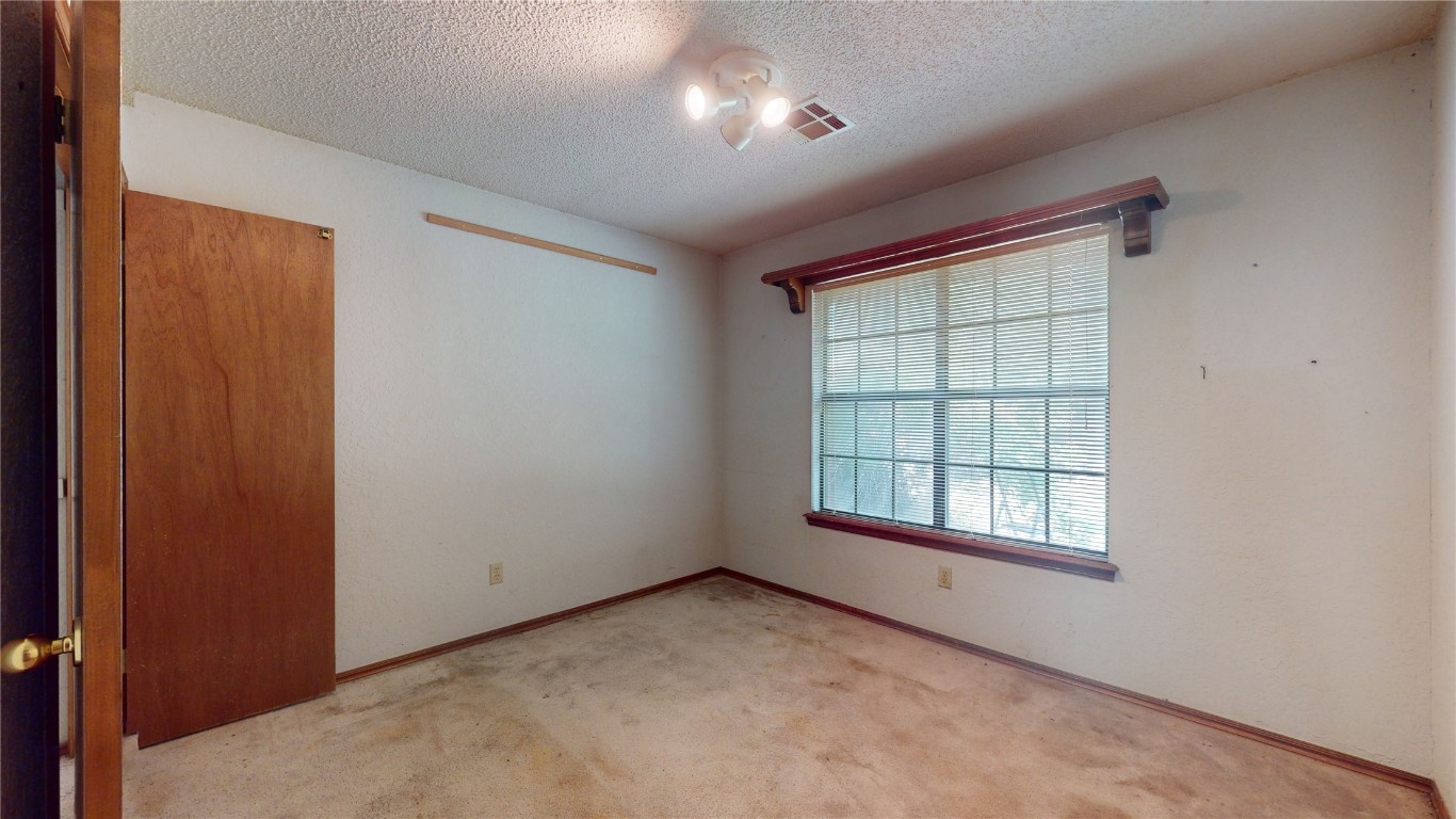 3100 SW 93rd Street, Oklahoma City, OK 73159 spare room with light carpet and a textured ceiling