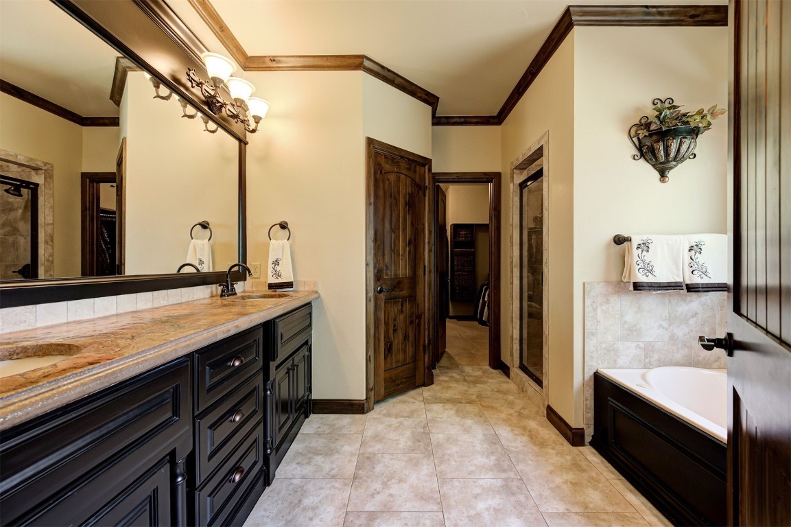 2123 Estancia Circle, Edmond, OK 73034 bathroom featuring large vanity, ornamental molding, and dual sinks