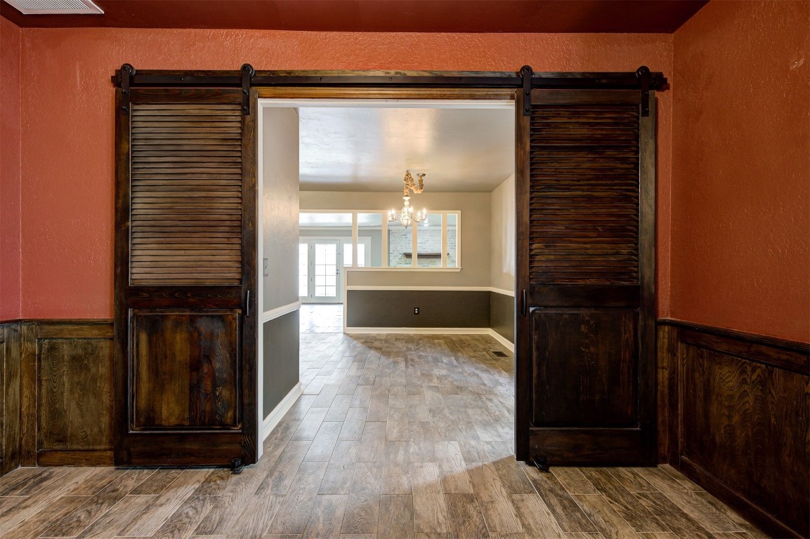 6712 Briarcreek Drive, Oklahoma City, OK 73162 corridor with hardwood / wood-style flooring, a barn door, and an inviting chandelier