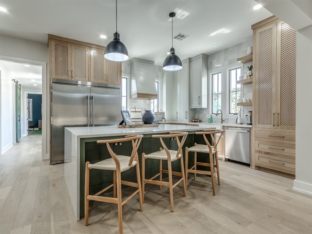 96 Walk in the Woods Lane, Carlton Landing, OK 74432 kitchen with decorative light fixtures, light hardwood / wood-style floors, appliances with stainless steel finishes, and custom range hood