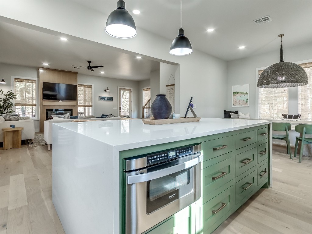 96 Walk in the Woods Lane, Carlton Landing, OK 74432 kitchen featuring a kitchen island, green cabinetry, stainless steel oven, pendant lighting, and light wood-type flooring