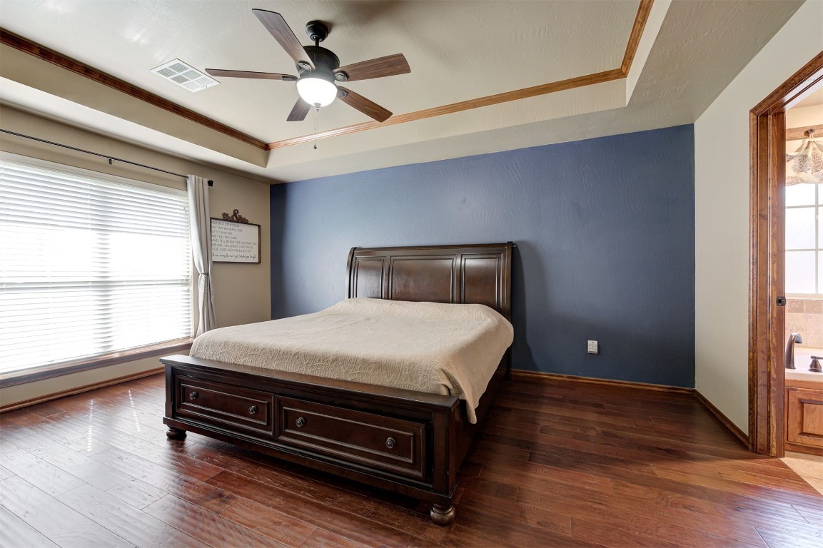 17208 Prado Drive, Oklahoma City, OK 73170 bedroom with ceiling fan, a raised ceiling, dark wood-type flooring, and connected bathroom