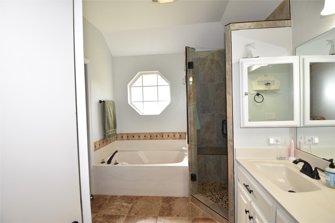 4200 Ainsley Court, Edmond, OK 73034 bathroom featuring tile floors, vanity, vaulted ceiling, and plus walk in shower