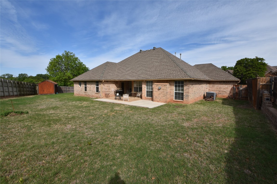 4200 Ainsley Court, Edmond, OK 73034 rear view of property with a patio, a lawn, a shed, and central AC