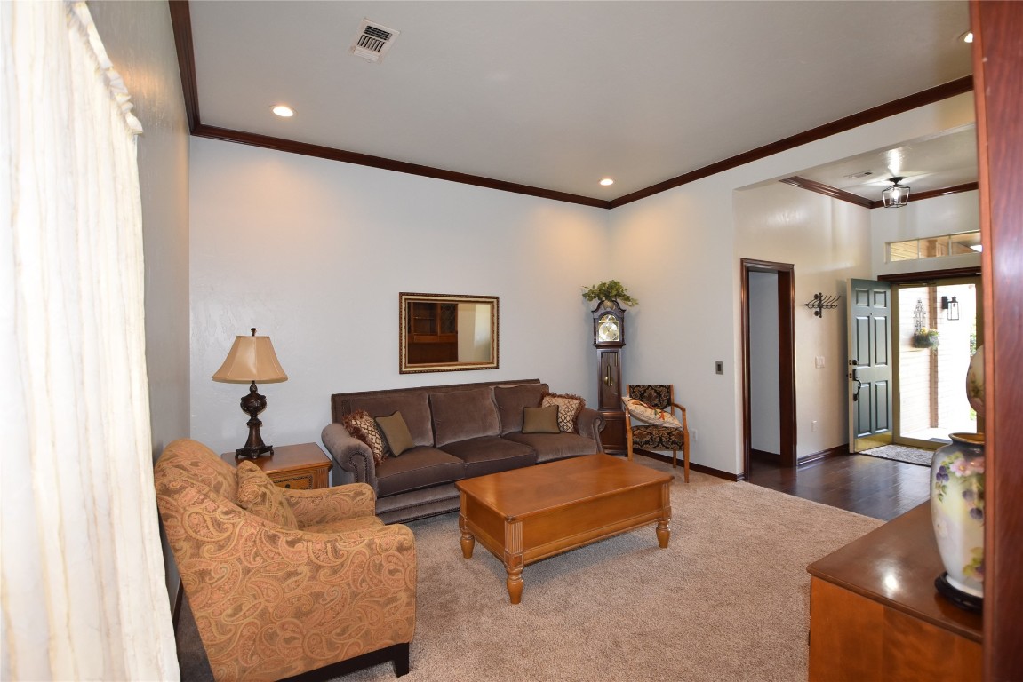 4200 Ainsley Court, Edmond, OK 73034 living room with ornamental molding and dark carpet