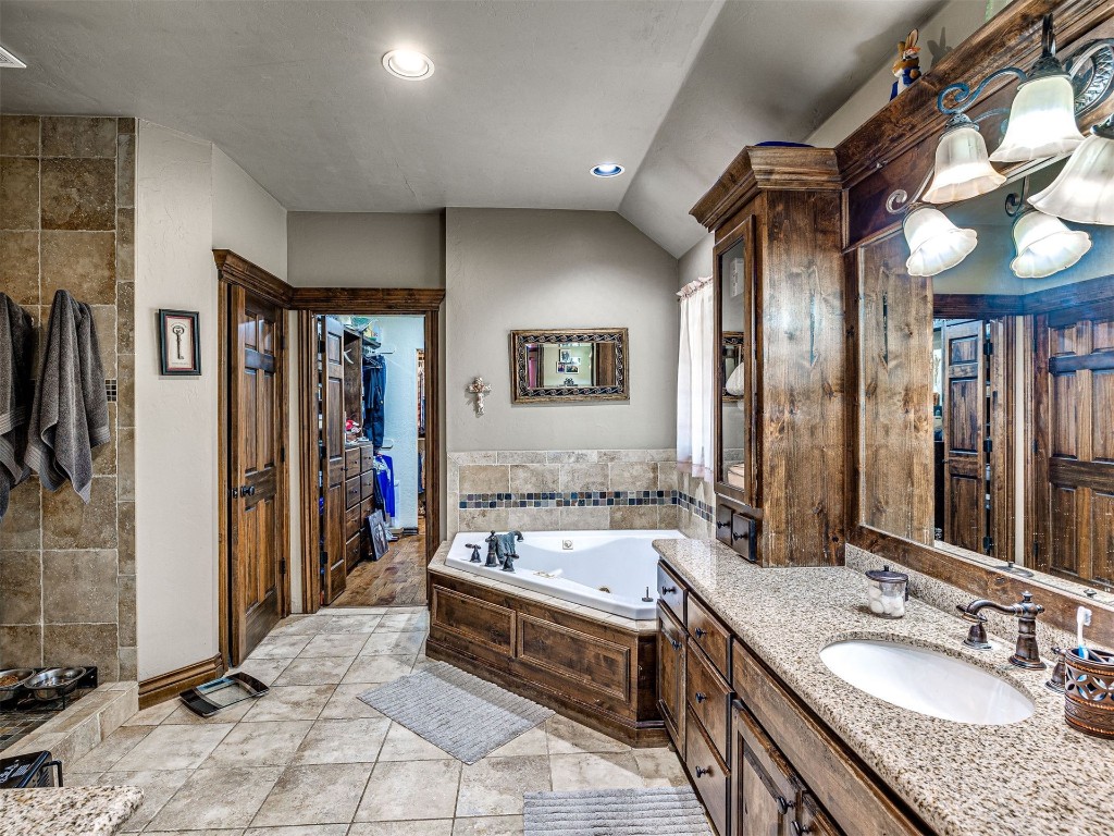 1580 NW 220th Street, Edmond, OK 73025 bathroom featuring lofted ceiling, oversized vanity, tile floors, and a bath to relax in