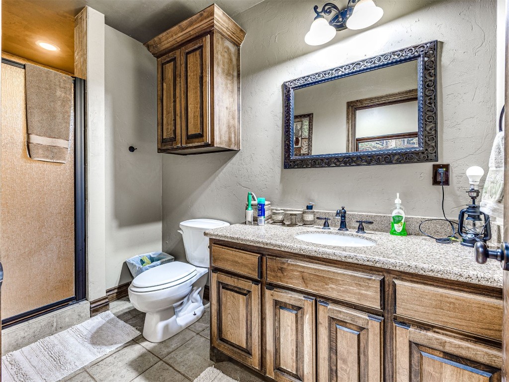 1580 NW 220th Street, Edmond, OK 73025 bathroom featuring tile floors, toilet, oversized vanity, and an enclosed shower