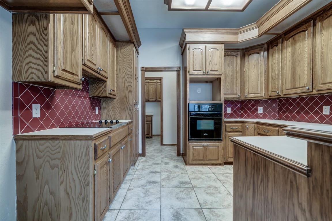 7416 NW 114th Terrace, Oklahoma City, OK 73162 kitchen featuring backsplash, black appliances, and light tile floors