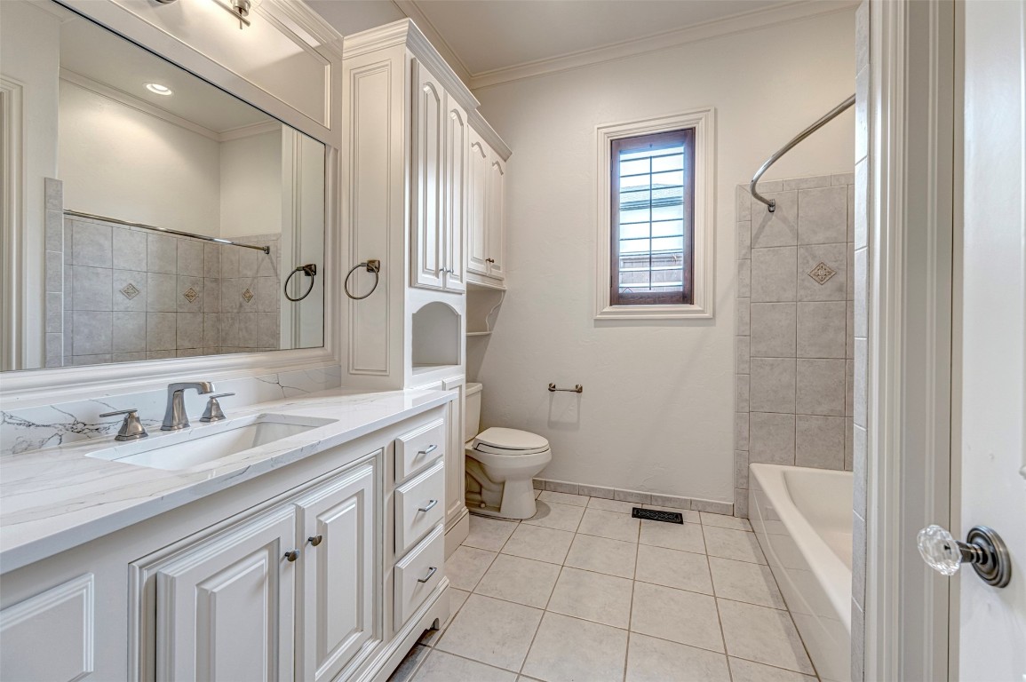 6516 NW Grand Boulevard, Nichols Hills, OK 73116 full bathroom featuring crown molding, tiled shower / bath combo, vanity, tile flooring, and toilet
