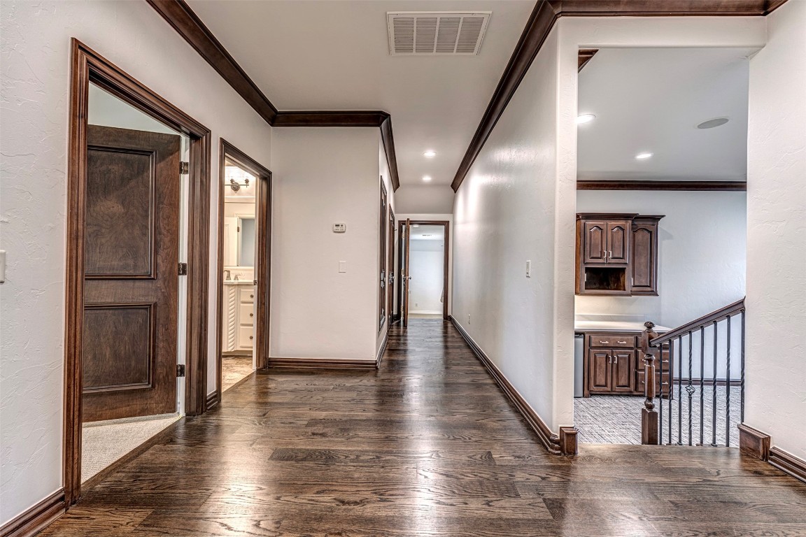 6516 NW Grand Boulevard, Nichols Hills, OK 73116 hallway with crown molding and dark wood-type flooring