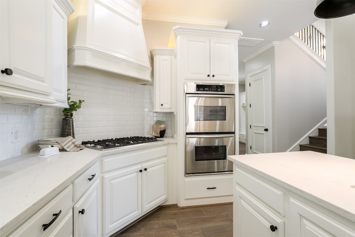 3624 Hunters Creek Road, Edmond, OK 73003 kitchen with appliances with stainless steel finishes, white cabinets, backsplash, dark wood-type flooring, and premium range hood