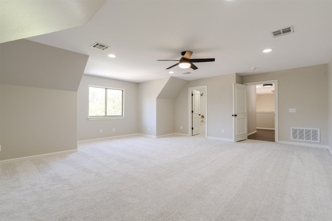 3624 Hunters Creek Road, Edmond, OK 73003 bonus room with light colored carpet, lofted ceiling, and ceiling fan
