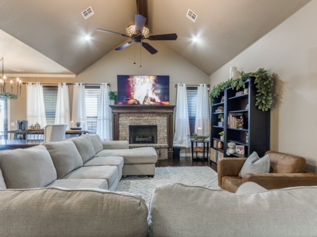 18309 Haslemere Lane, Edmond, OK 73012 living room featuring wood-type flooring, ceiling fan with notable chandelier, and vaulted ceiling