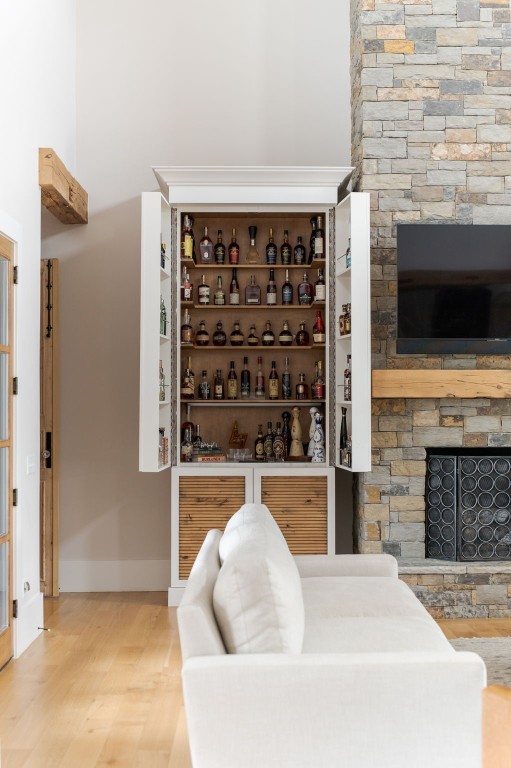 9301 Farmhouse Lane, Arcadia, OK 73007 wine room with hardwood / wood-style flooring and a stone fireplace