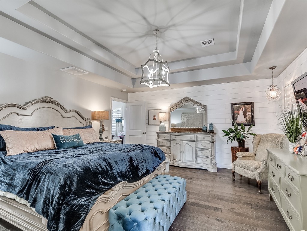 8000 NW 67th Place, Warr Acres, OK 73132 bedroom with wood-type flooring, a notable chandelier, and a tray ceiling