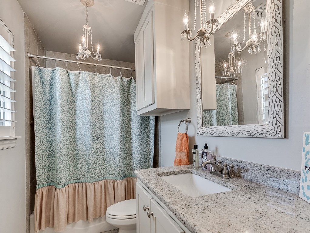 8000 NW 67th Place, Warr Acres, OK 73132 bathroom featuring vanity, toilet, and an inviting chandelier