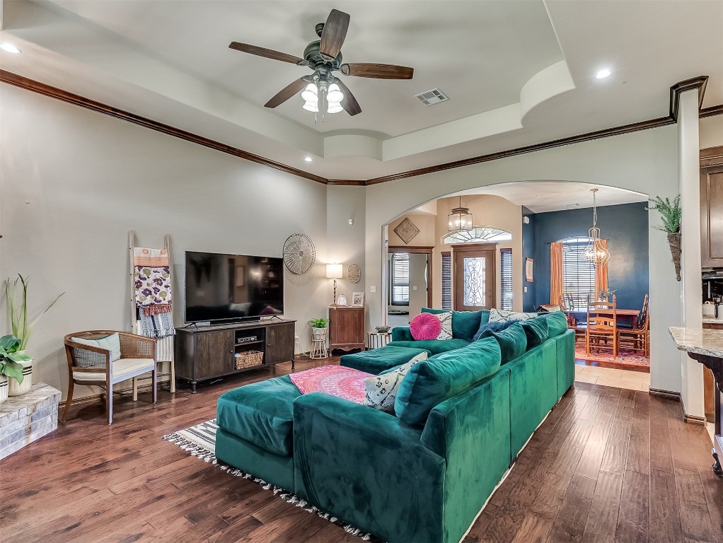 705 Evening Drive, Yukon, OK 73099 living room with ceiling fan with notable chandelier, ornamental molding, dark hardwood / wood-style flooring, and a raised ceiling