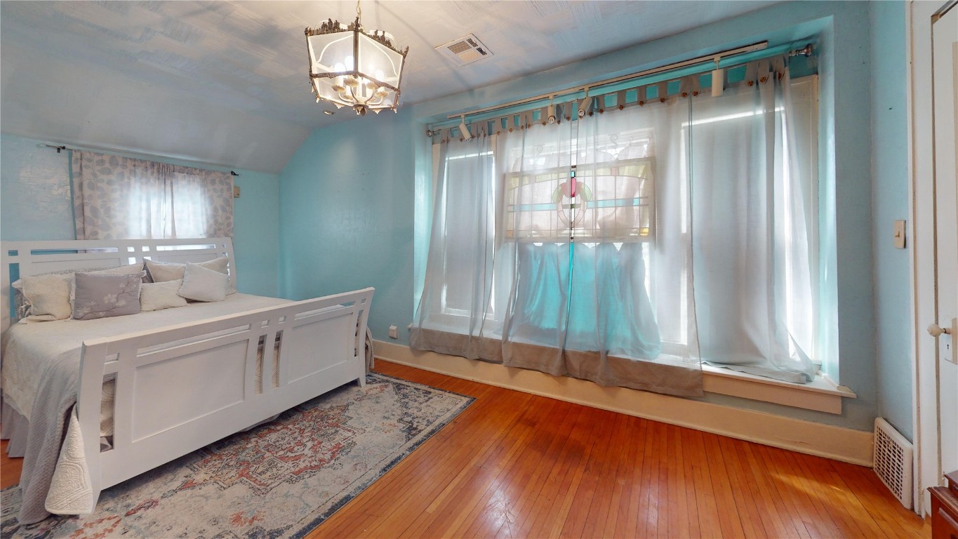 Address Hidden bedroom featuring vaulted ceiling, light hardwood / wood-style floors, a notable chandelier, and multiple windows