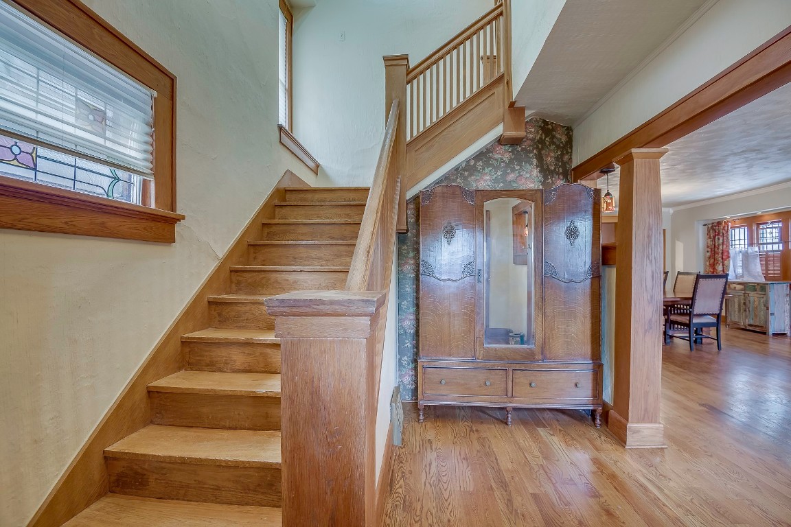 Address Hidden stairs featuring hardwood / wood-style flooring, ornamental molding, and decorative columns