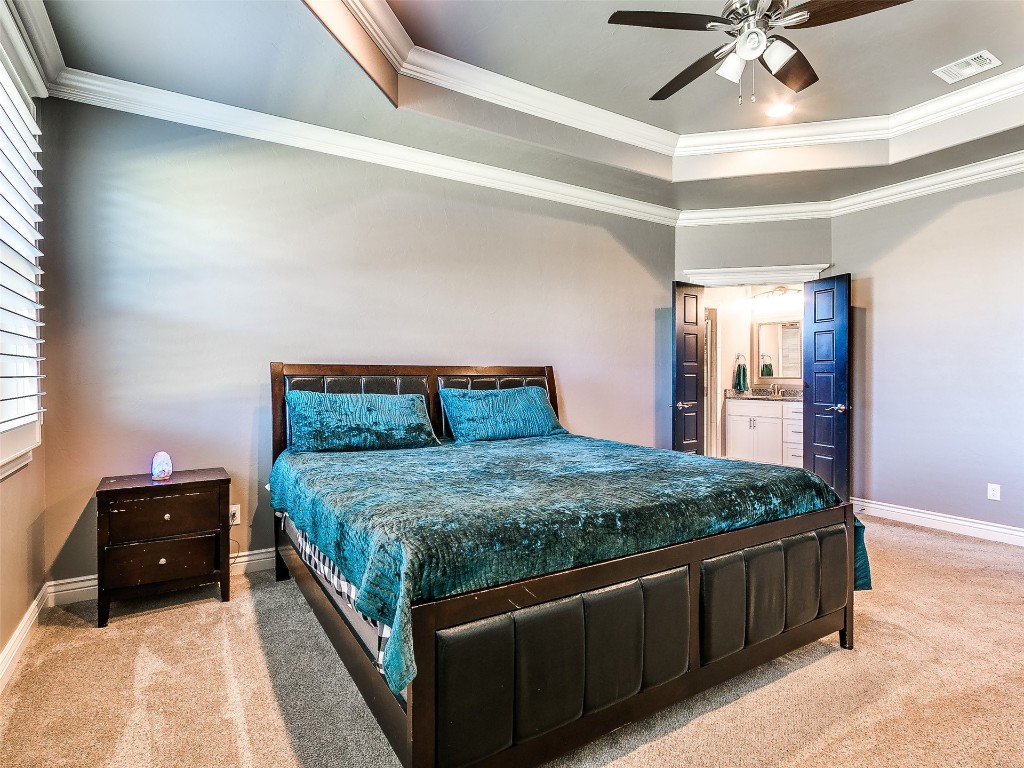15820 Rockwell Park Lane, Edmond, OK 73013 bedroom featuring crown molding, ceiling fan, and a tray ceiling