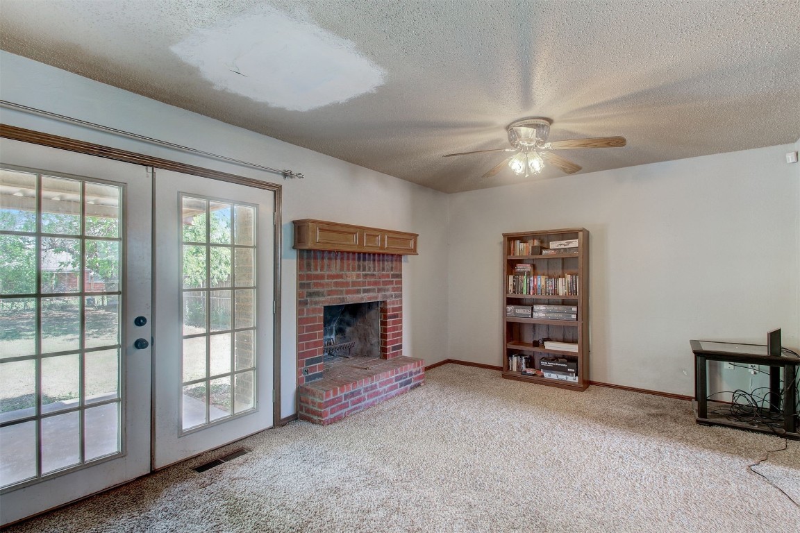 4001 Chetwood Drive, Del City, OK 73115 unfurnished living room featuring light colored carpet, french doors, ceiling fan, and a brick fireplace