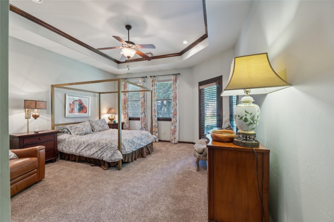 2147 Bridgeview Boulevard, Edmond, OK 73003 carpeted bedroom featuring ceiling fan and a tray ceiling