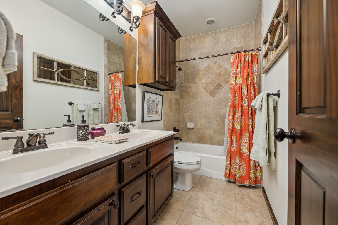 2147 Bridgeview Boulevard, Edmond, OK 73003 full bathroom with double sink vanity, shower / bath combo with shower curtain, toilet, and tile flooring
