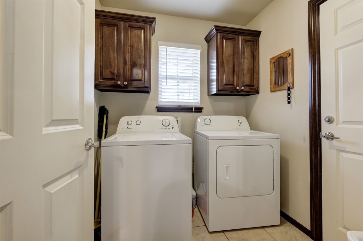 11748 SW 21st Street, Yukon, OK 73099 laundry room with cabinets, light tile floors, and washing machine and clothes dryer