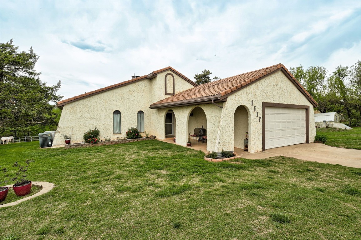 1517 S Spring Creek Drive, Mustang, OK 73064 mediterranean / spanish home with a front yard, a garage, and central AC