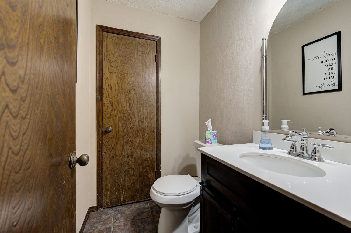1517 S Spring Creek Drive, Mustang, OK 73064 bathroom featuring tile floors, vanity, toilet, and a textured ceiling